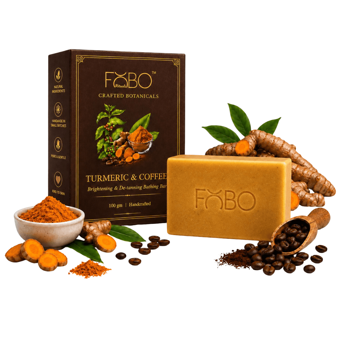 A bar of F&BO Turmeric & Coffee handcrafted soap displayed next to its dark brown packaging box, surrounded by ingredients including turmeric roots, coffee beans, and green leaves on a white background.